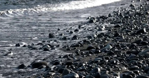 Waves Rolling in on a Pebble Coast Line With Glistening and Shimmering Sea Stock Footage 72080881