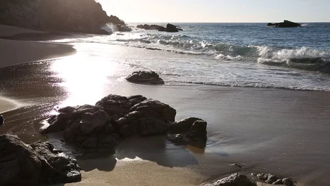 Waves rolling onto sand at tropical beach during sunset Stock Footage