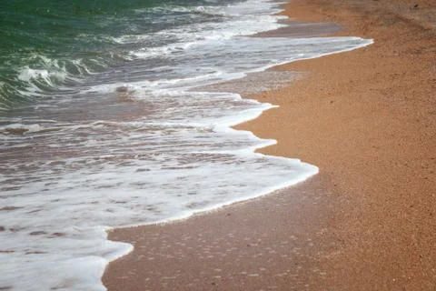 Waves rolling to the sandy beach Stock Photos