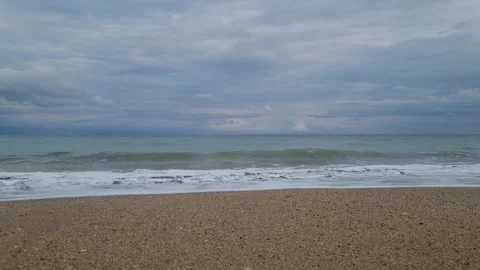 Waves rolling onto sandy beach under cloudy sky, calm sea horizon Stock Footage 320134258