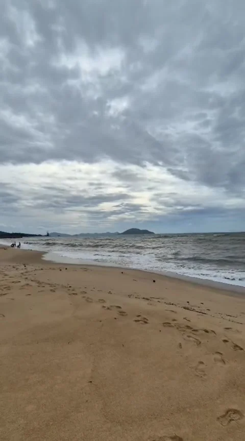 Waves Rolling onto a Sandy Tropical Beach Under Cloudy Sky Stock Footage 344879728