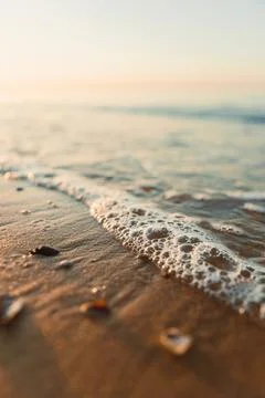 Waves rolling onto the shore with sunlight creating a warm glow over the wa.. Foto stock