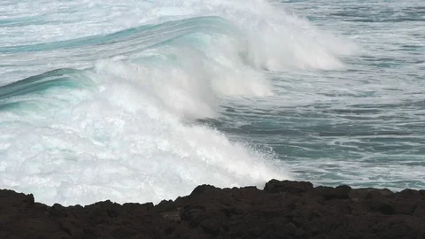 Waves rolling by a volcanic dark cliff Stock Footage 115909033