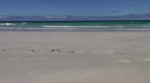 Waves rolling in on white sand beach with blue sky Stock Footage 975986