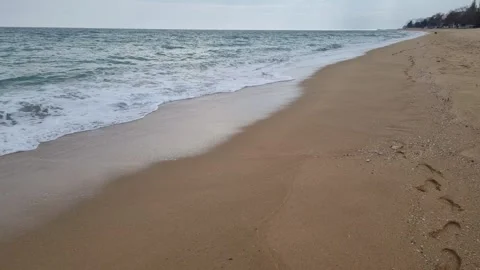 Waves rolling onto wide sandy beach under cloudy coastal autumn sky Stock Footage 321651129