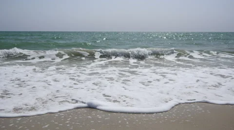 Waves running on the sandy shore leaving a foam Stock Footage 64338860