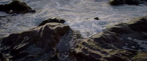 Waves rush over rocks in evening Stock Footage 136448732