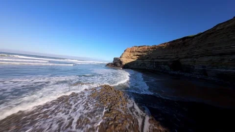 Waves rush over rocky shore near steep cliffs; Ribeira D'Ilhas 库存影片 346371683