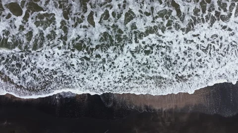 Waves rush to shore as the tide changes at a beach, creating a pattern of foam Stock Footage 336527717