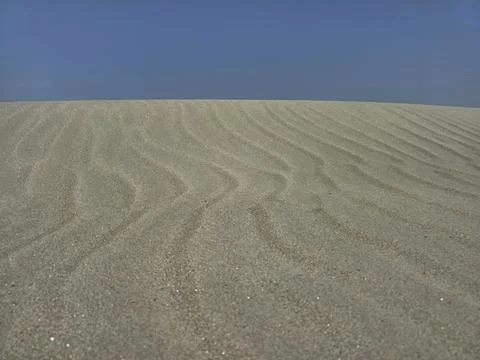 Waves of sand and blue sky Stock Photos