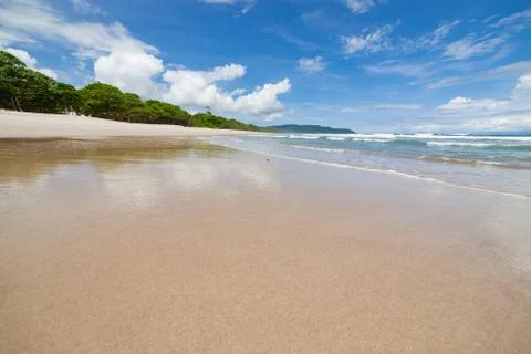 Waves sand beach and clouds sunny day Stock Photos