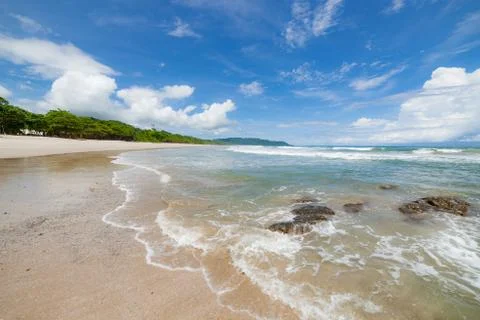 Waves sand beach and clouds sunny day Stock Photos