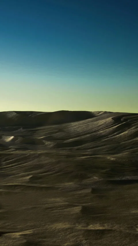 Waves of sand dance under a vast sky at twilight in a tranquil desert landscape Video stock 334254673