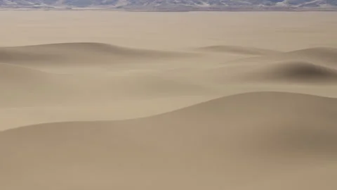 Waves of sand form patterns in a desert landscape under a clear sky Vidéo 344141233