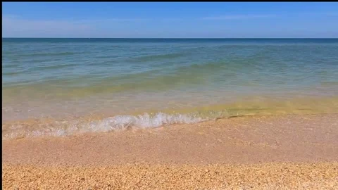 Waves onto sandy beach in clear weather. Warm sand meets blue, turquoise sea.  Stock Footage 302154368