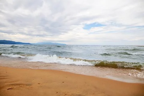 Waves on a sandy beach on a cloudy day Stock Photos