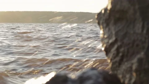 Waves of the sea are breaking on the cliffs of the coast. Sun rays Видео 133138075