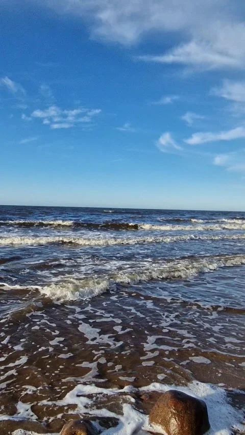 Waves on the sea in clear weather on a sandy beach with stones Stock Footage 298723694