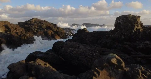 Waves with sea foam splashing on rocky coastline Stock Footage