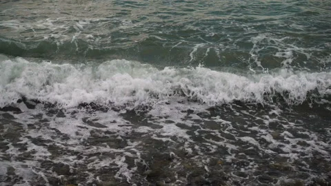 The waves of the sea foaming over the pebbled shore Stock-Footage 89997835