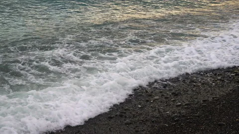 The waves of the sea foaming over the pebbled shore Stock Footage 89998187
