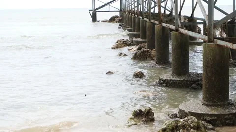 The waves of the sea hit the concrete pillars of the beach bridge Stock Footage 319386261