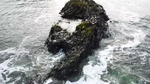 Waves of the sea lash against a pair of lichen &amp; algae topped rocks. Stock Footage 303678125