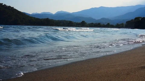Waves of the sea on a sandy beach with mountains in the background. Stock Footage 108078338