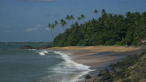 Waves of the sea surf roll on a sandy rocky beach against the backdrop of a blue 스톡 동영상 223360351