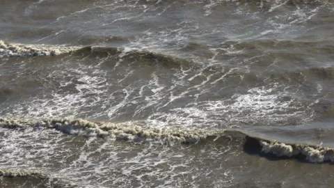 Waves on seashore in sunny weather.  Cloudy water, top view. 動画素材 153589596