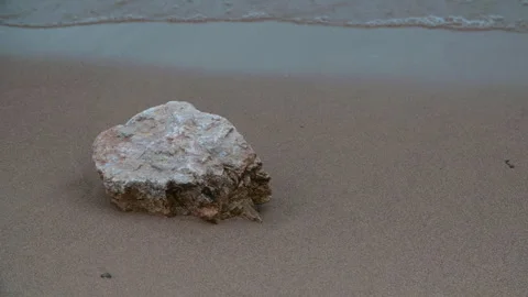 Waves in slow motion roll up to a rock lying on the seashore Vídeos de archivo 289808484