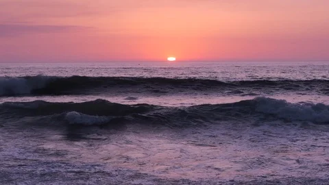 Waves in slow motion at sunset as sun disappears below horizon in the distance Stock Footage 115920181