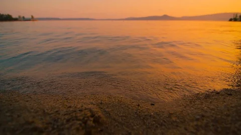The waves slowly beat against the shore of the lake at sunset Stock Footage 106210272