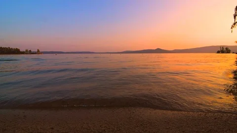 The waves slowly beat against the shore of the lake at sunset Stock Footage 106210397