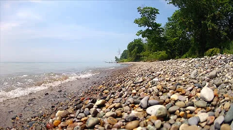 Waves slowly lap against the river rock on the shores of Lake Erie, Ontario Stock Footage 25324134