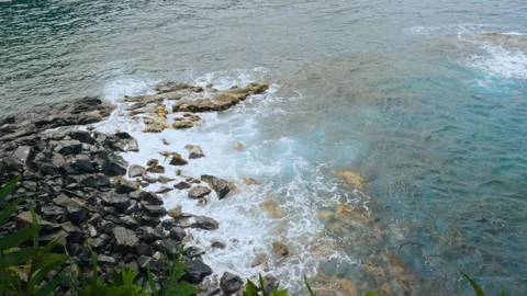Waves slowly roll over black rocks of a volcanic beach. A view of tidal wave Video stock 275003304