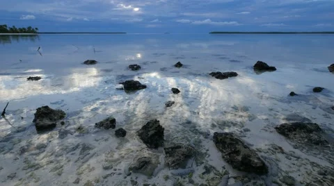 Waves slowly splashing on the sand and small rocks at sunset Stock Footage 68698994
