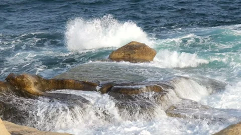 Waves splash against golden lit limestone rocks evening surf texture along the Stock Footage 341807939