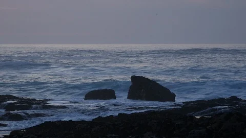 Waves splash over dark rocks on the coast at dusk / early evening Stock Footage 103066525