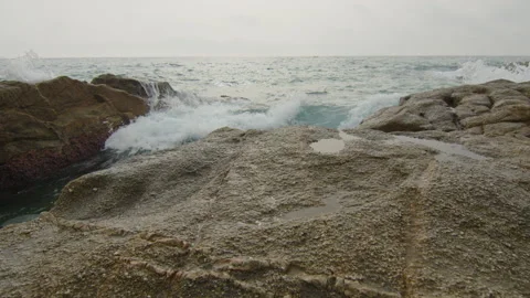 Waves splash on the rocks of the beachfront, in Spain Stock Footage 230098458