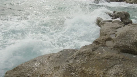 Waves splash on the rocks at the edge of the sunny beach, in Spain Stock Footage 230095912