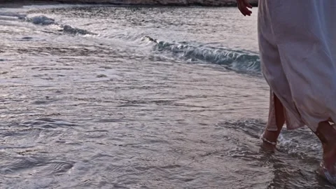 Waves splash at the shore while a person walks along the beach during sunset Stock Footage 342787116