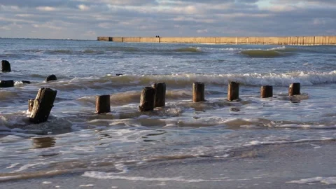 Waves splashing against old remains of wooden breakwater Stock Footage 244065961