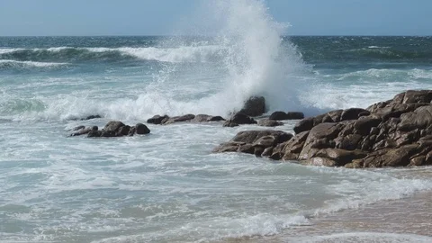 Waves splashing against rocks on beach, on a bright sunny day in summer Stock Footage 115787962