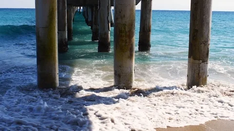 Waves splashing against supports under a pier Stock Footage 108642623