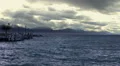 Waves splashing on choppy water surface, stormy cloudscape, mountains on horizon HD Footage