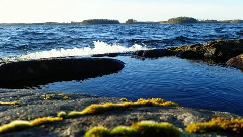Waves splashing droplets on a puddle at Nordic lake shore Stock Footage 86178026