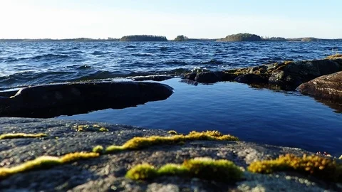 Waves splashing over a puddle at Nordic lake shore Stock Footage 86027787