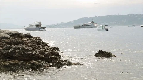 Waves splashing at rock stone at seashore coast with luxurious yachts in sea bay Stock Footage 70681559