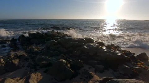 Waves splashing on rocks at beach at sunset, super slow motion. Video stock 133980023